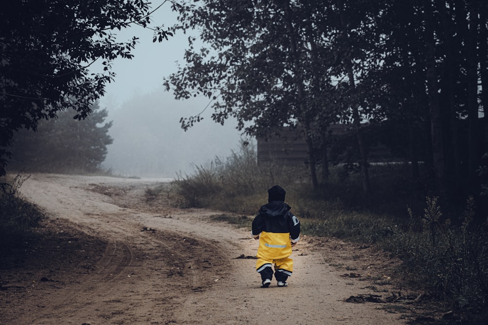 man in black jacket sitting on yellow and black wheelchair on brown dirt road during daytime