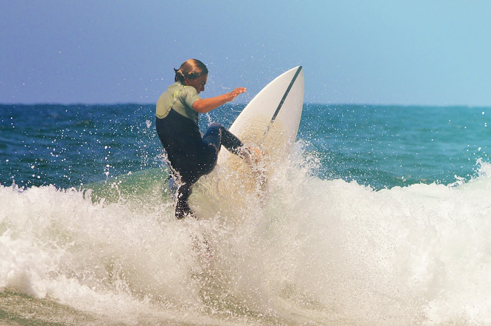 man in yellow and black wet suit surfing on sea waves during daytime