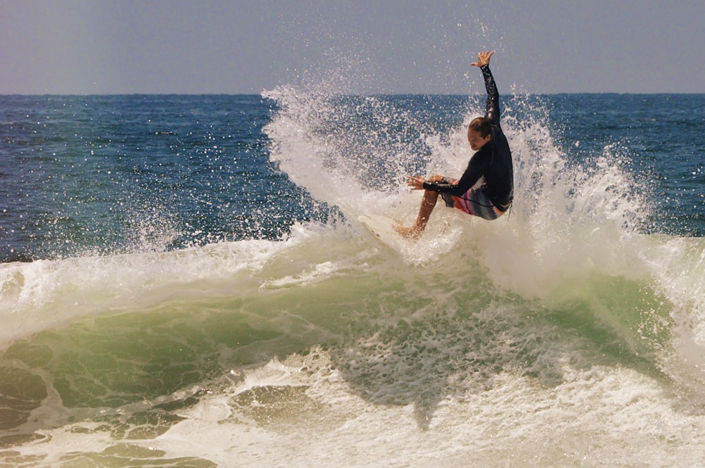 man in black wetsuit surfing on sea waves during daytime