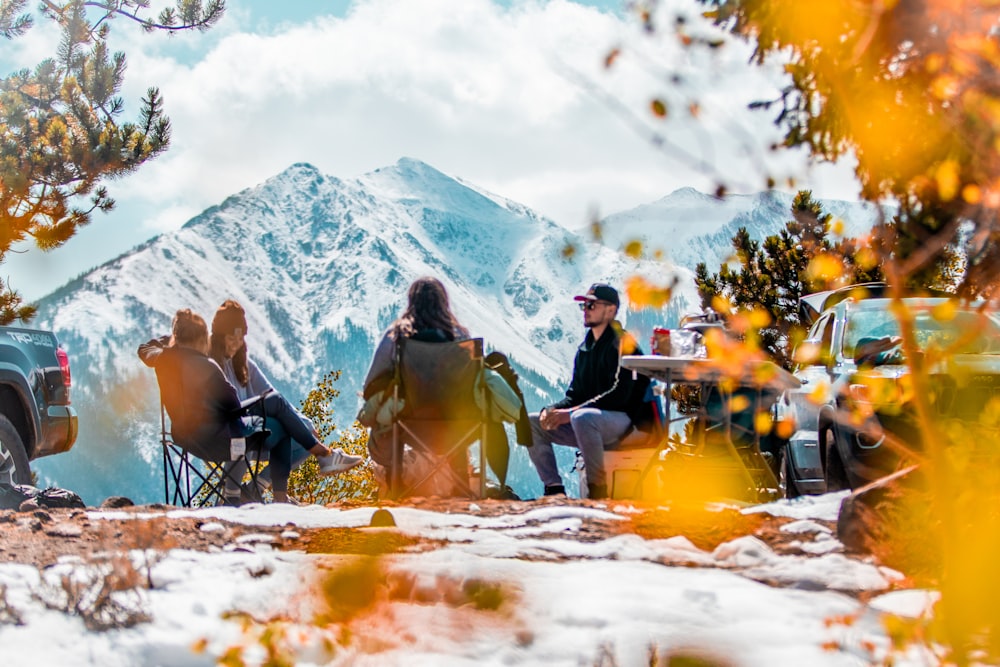 Personas sentadas en sillas de camping en un terreno cubierto de nieve durante el día