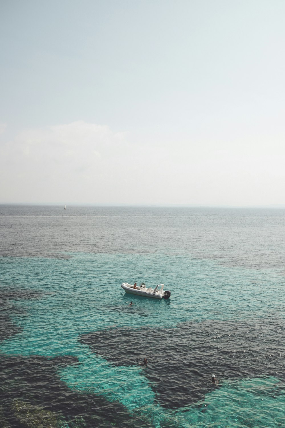 white boat on sea under white sky during daytime