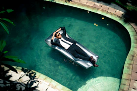 woman in black and white dress lying on pool side during daytime
