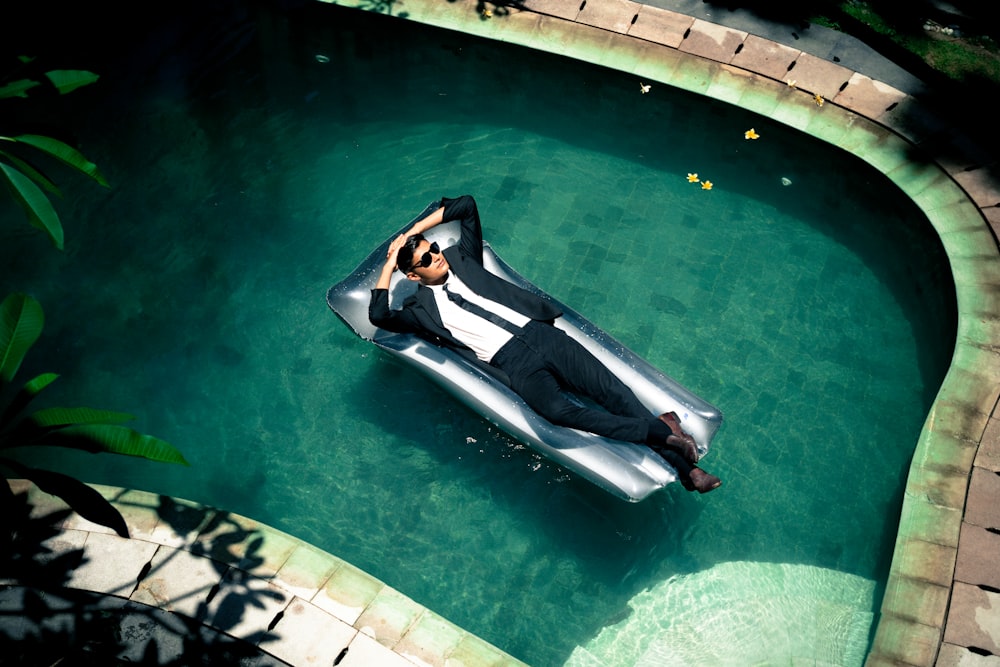 femme en robe noire et blanche allongée au bord de la piscine pendant la journée