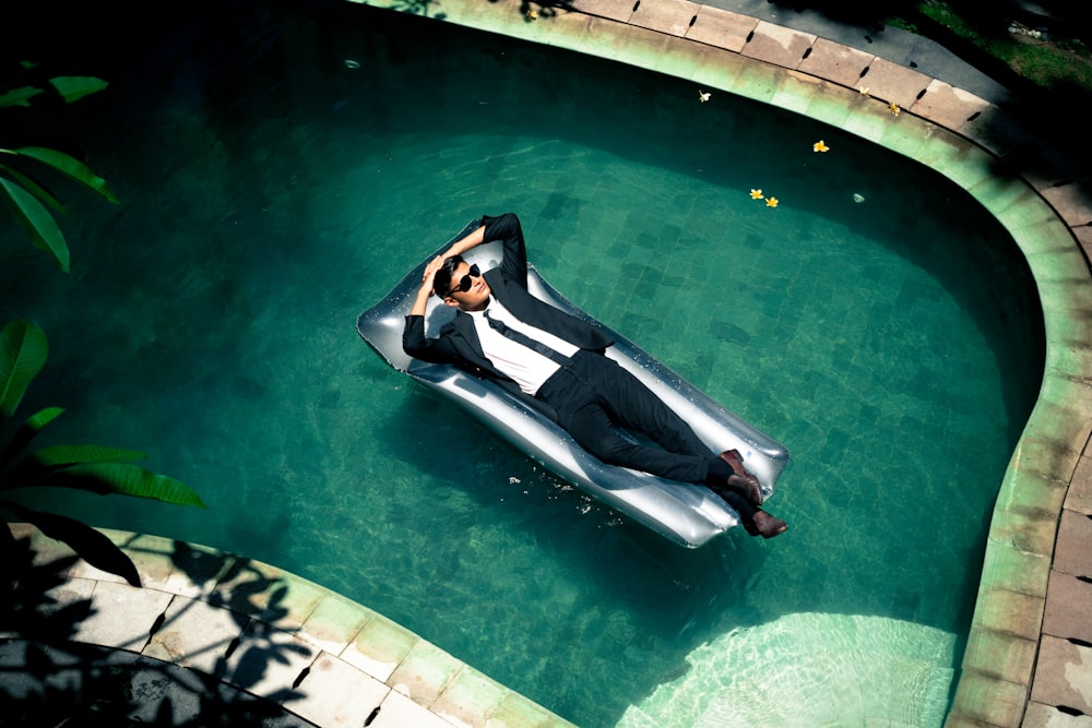 Donna in vestito bianco e nero che si trova sul lato della piscina durante il giorno