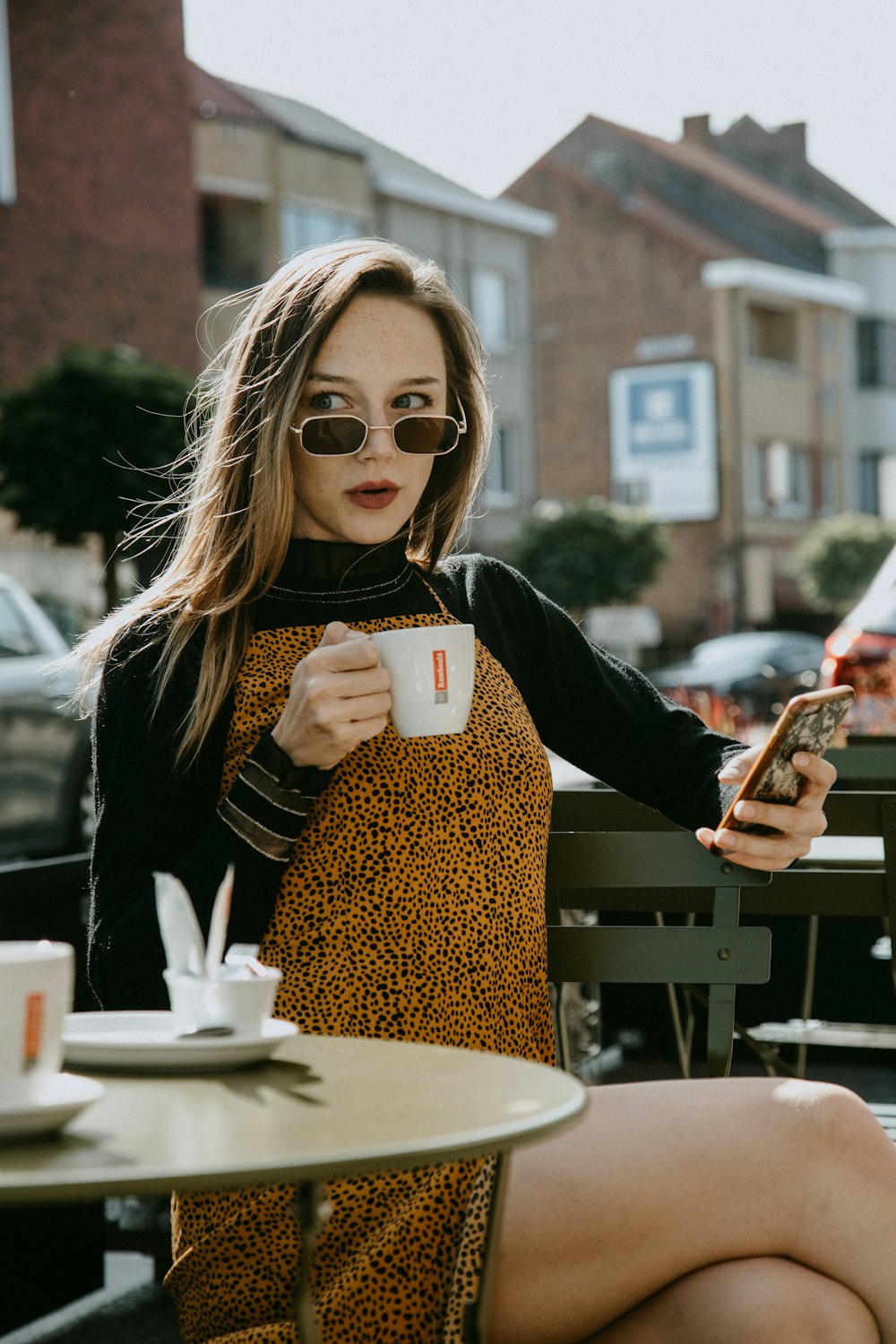 woman in black and brown leopard long sleeve shirt holding white ceramic mug