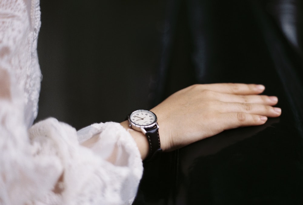person wearing silver round analog watch