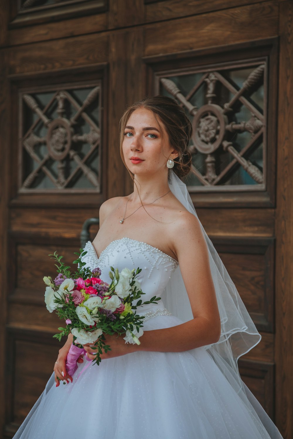 woman in white wedding dress holding bouquet of flowers