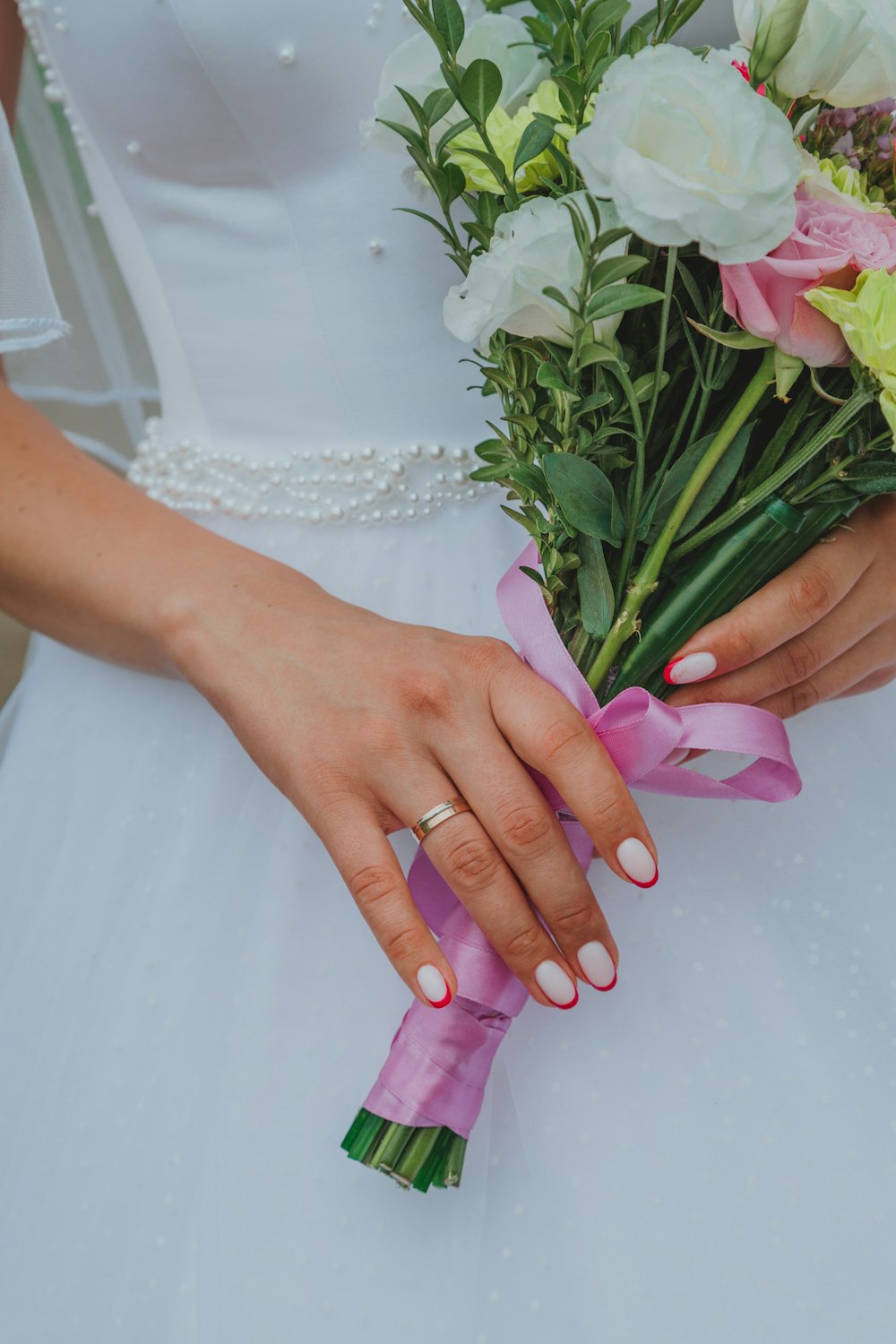 Mujer con vestido de novia blanco sosteniendo un ramo de tulipanes rosa