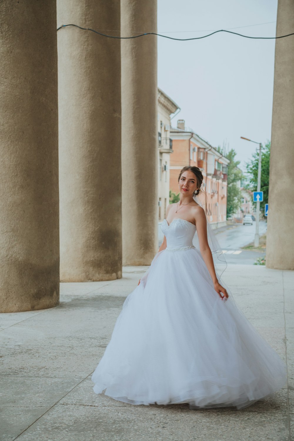 woman in white wedding dress standing near gray concrete building during daytime