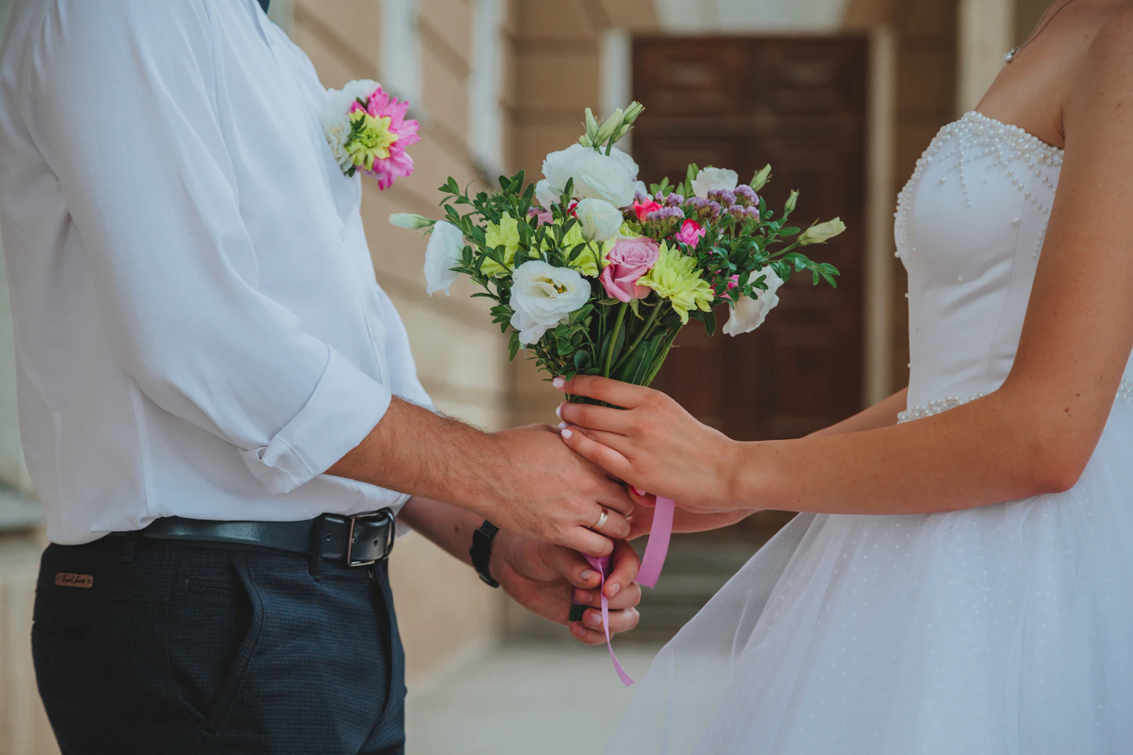 Bride and groom holding wedding bouquet together