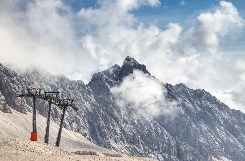 brown wooden ladder on brown field near snow covered mountain under white clouds during daytime