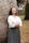woman in white long sleeve shirt and black skirt standing beside brown tree during daytime