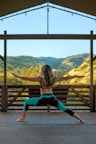 woman in black tank top and blue denim shorts sitting on brown wooden railings during daytime