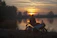 A rider smiling on a motorcycle overlooking a stunning mountain landscape at sunset.
