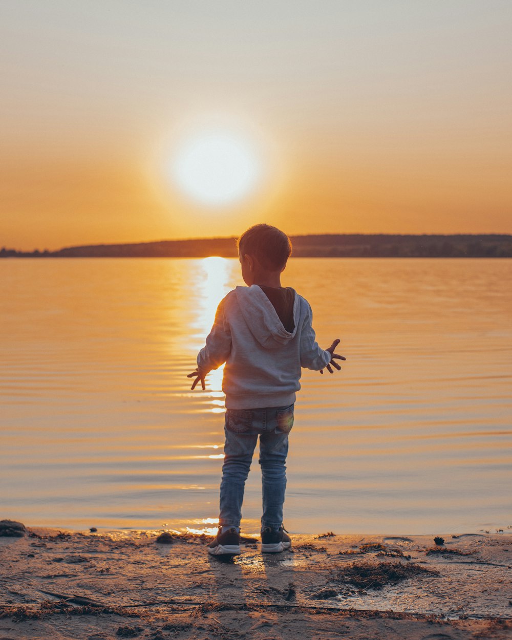 man in white long sleeve shirt and brown pants carrying baby in white jacket on beach