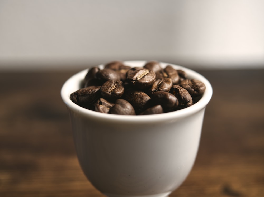 taza de cerámica blanca con granos de café marrones