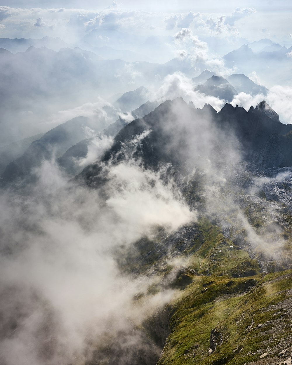 green grass covered mountain under white clouds during daytime