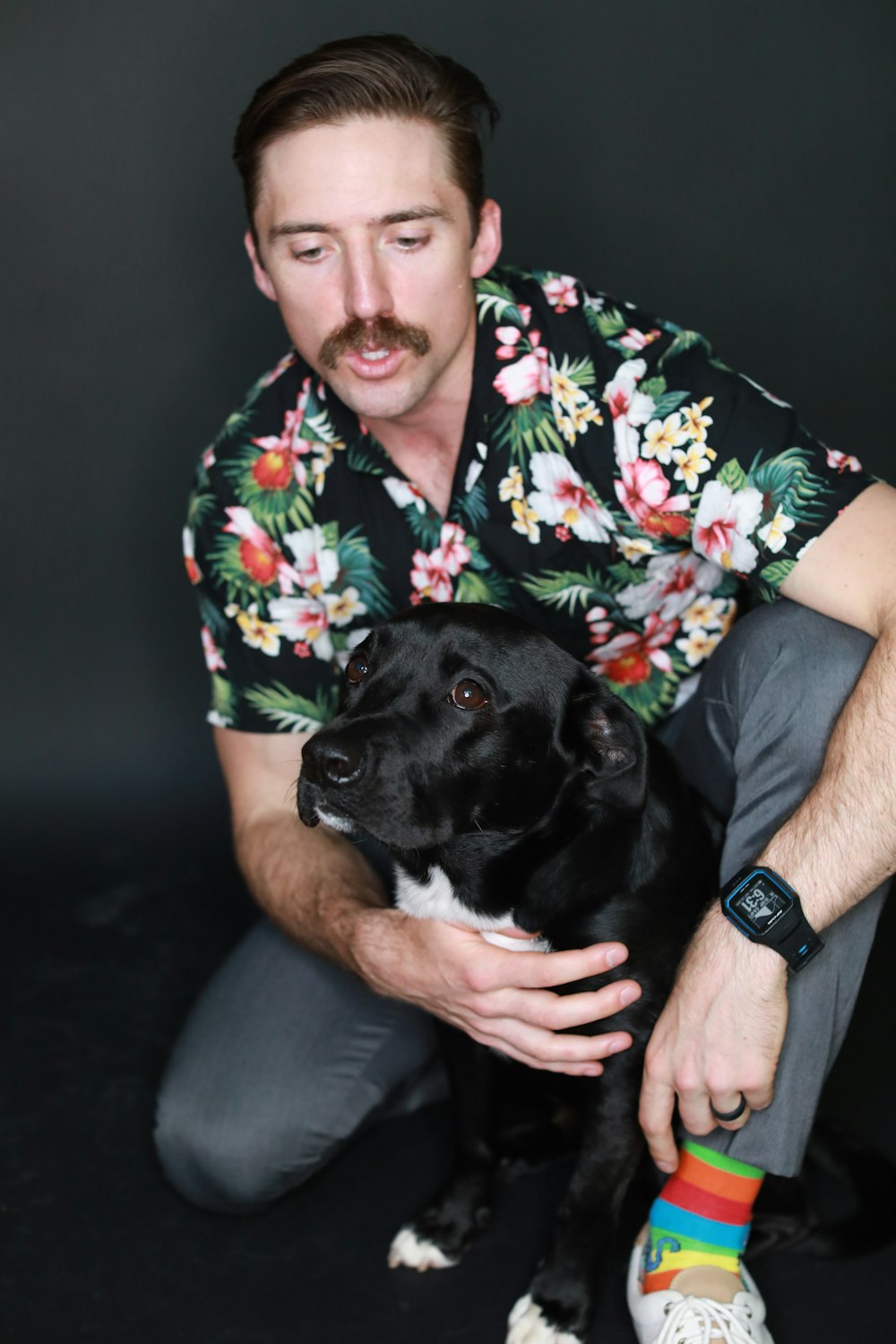 man in red green and white floral button up t-shirt sitting beside black short coated