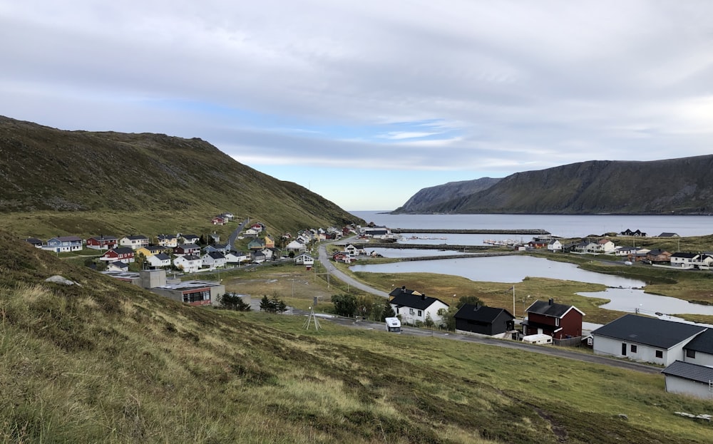 white and brown houses on green grass field near lake and mountains during daytime