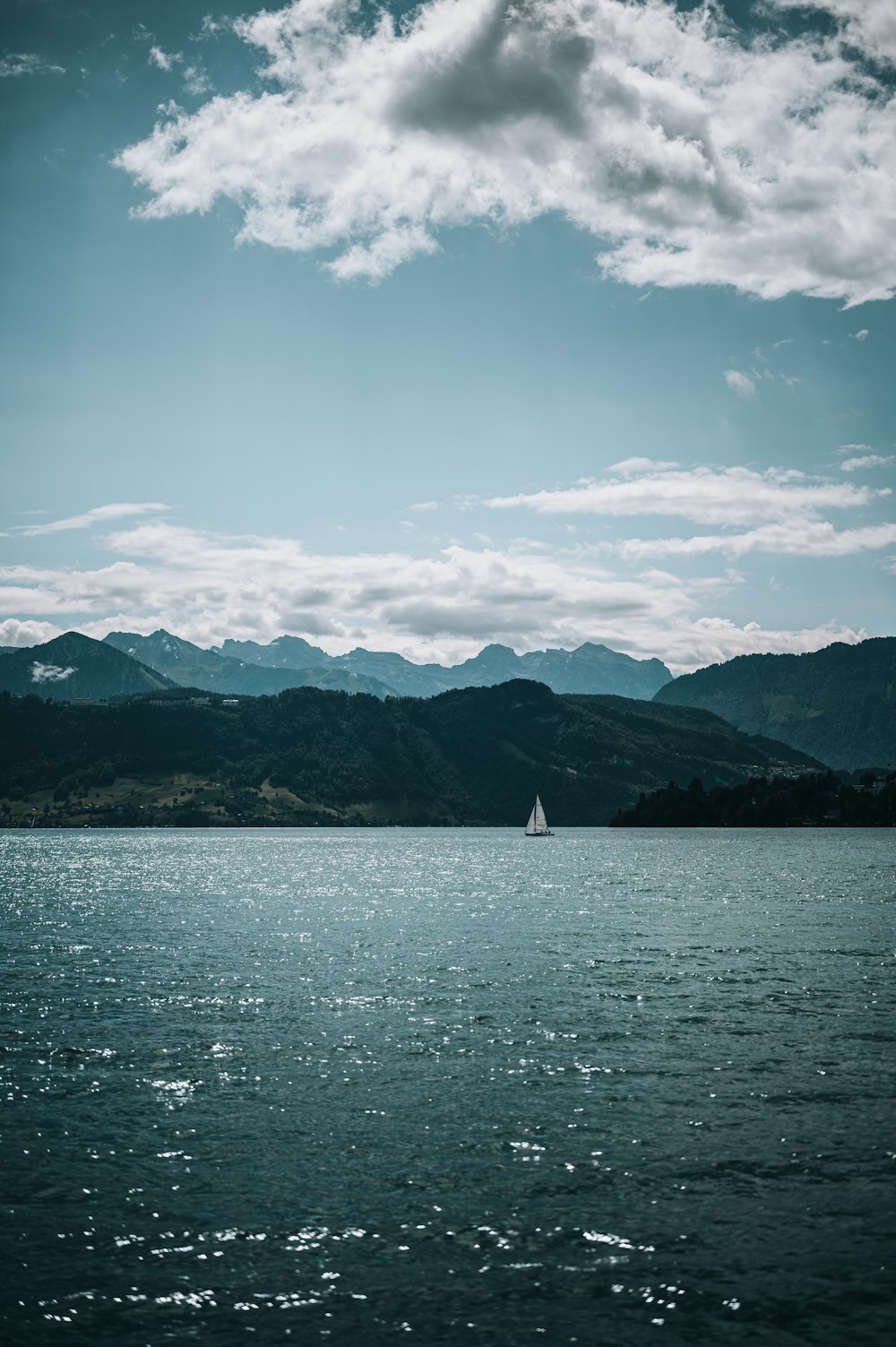 white sailboat on sea near mountain under blue sky during daytime