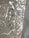 A concrete surface with splatters of white and black paint scattered across it in an abstract pattern. The texture of the concrete is visible, and the paint splatters vary in size, with some appearing as small dots and others as larger, irregular blobs. There are also fine lines of paint running across the surface, adding to the chaotic appearance.