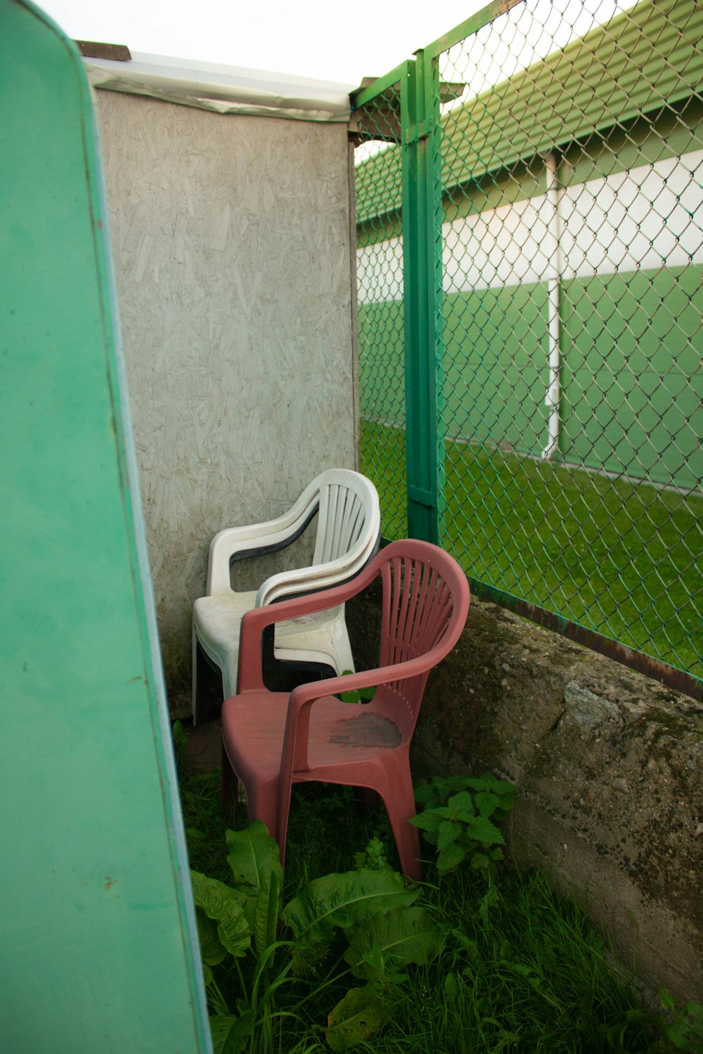 white plastic armchair beside green wall
