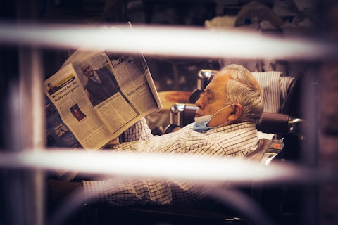 grayscale photo of man reading newspaper
