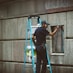 man in blue t-shirt and blue pants standing on ladder