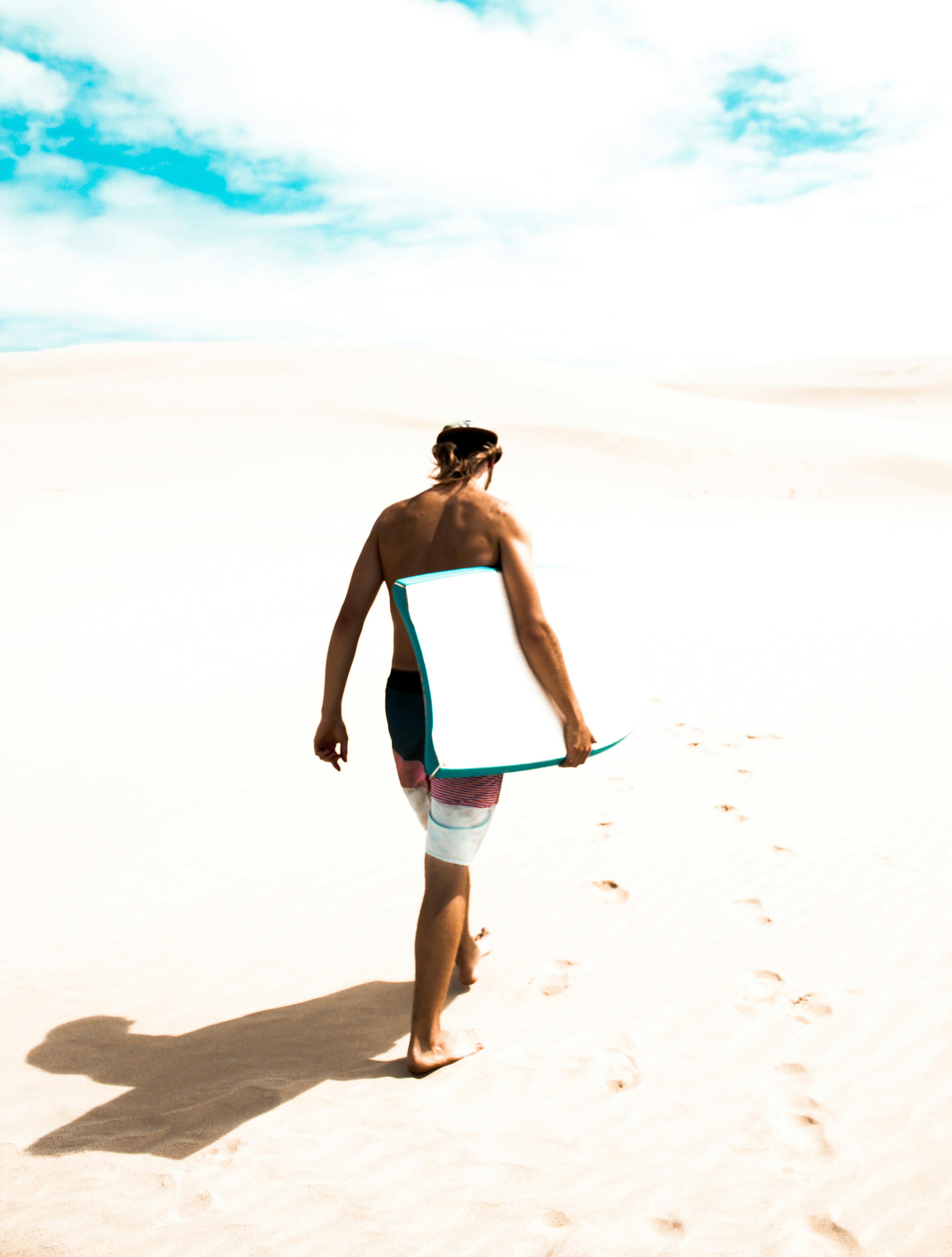 woman in blue tank top and blue denim shorts walking on beach during daytime