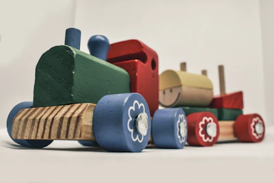 A colorful wooden train set with bright red, blue, and yellow cars on a smooth track.