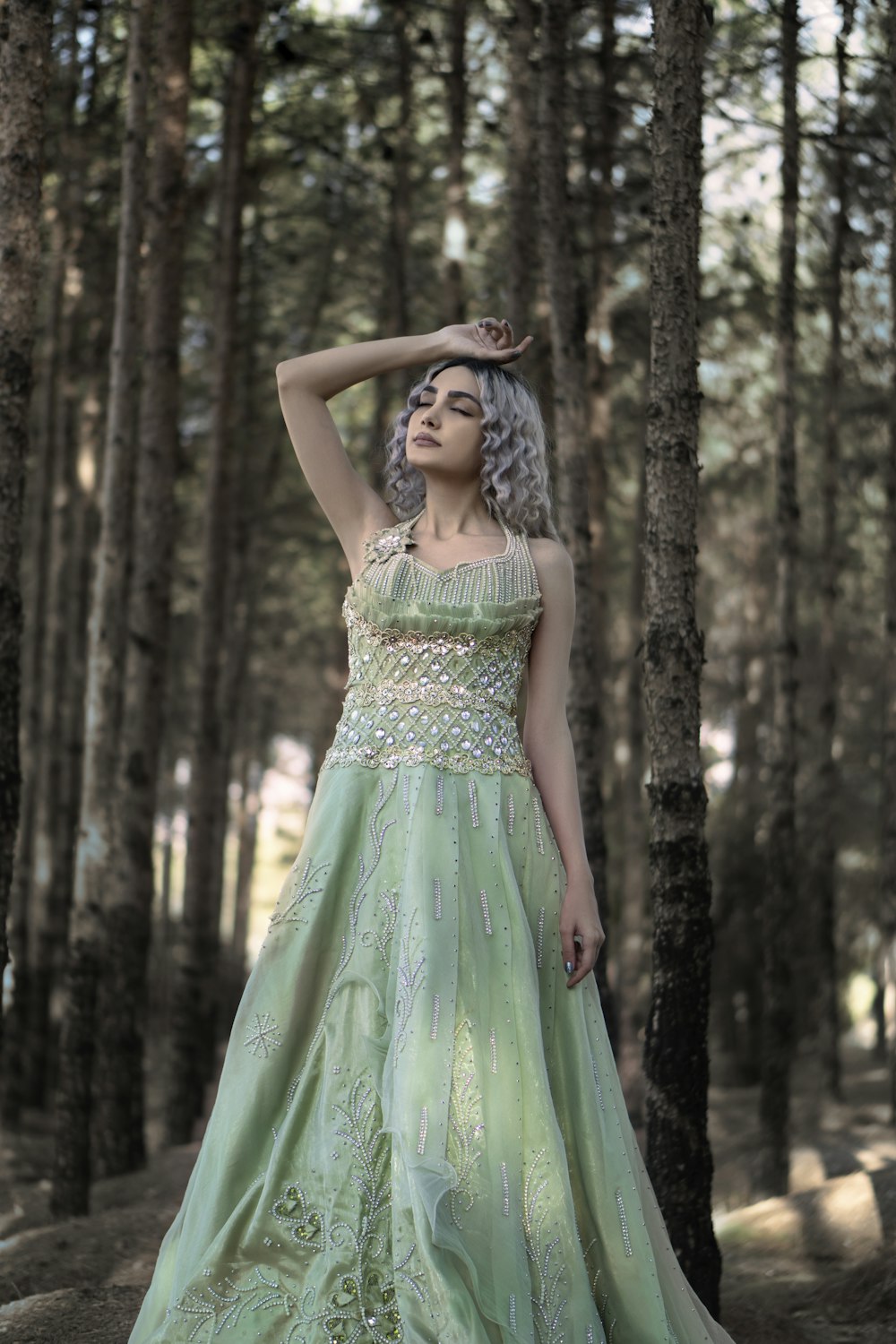 Femme en robe verte debout près des arbres pendant la journée