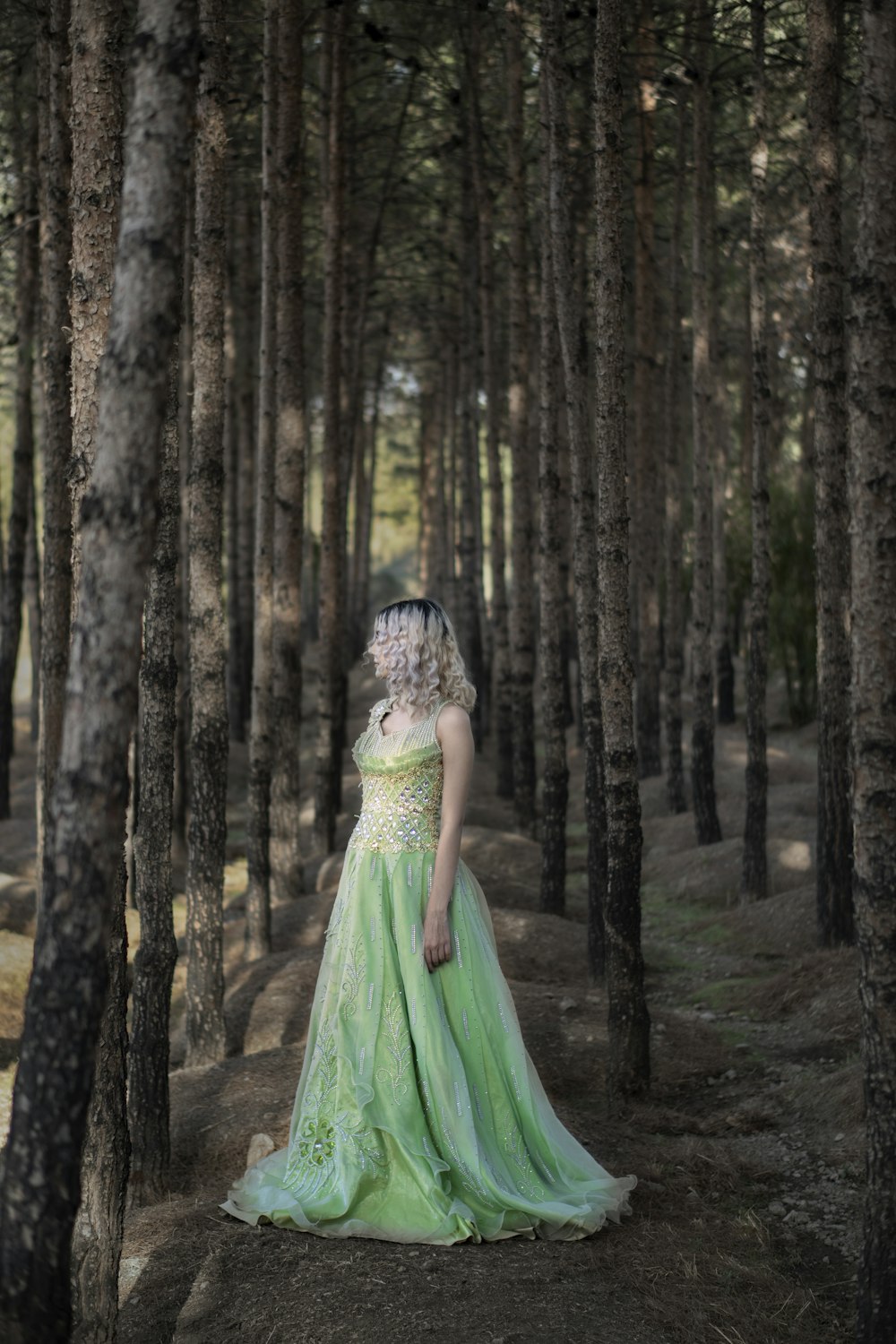 woman in green dress standing in the woods