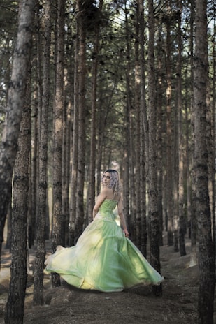 A model wearing a flowing midi dress in a forest setting.