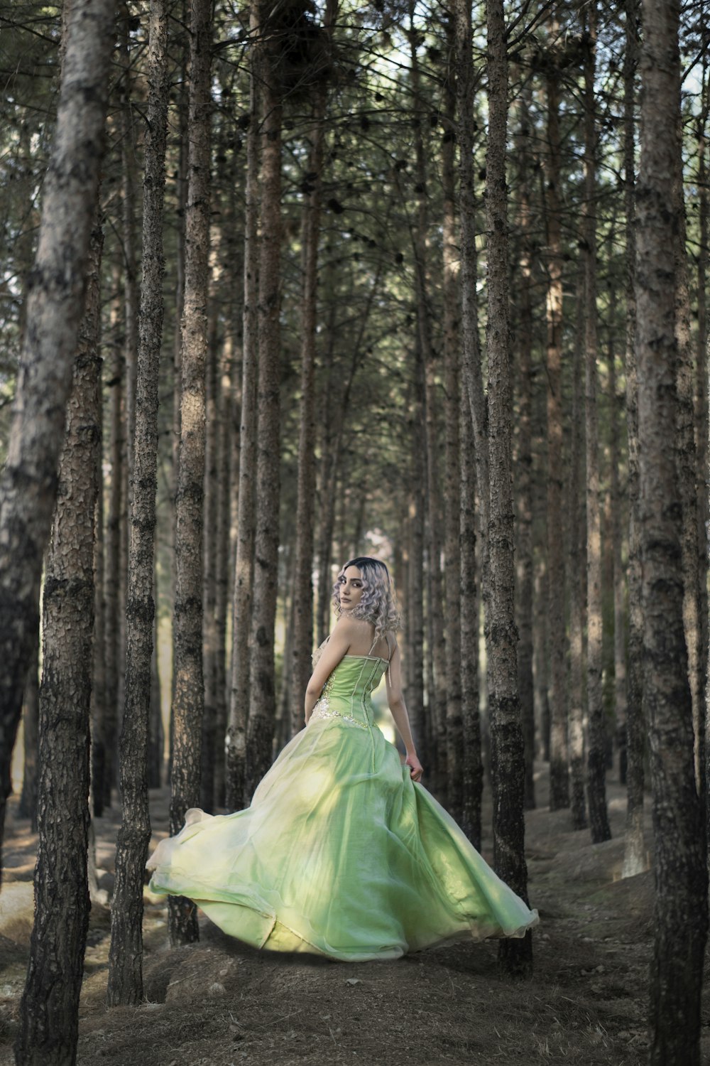 Femme en robe verte debout dans les bois