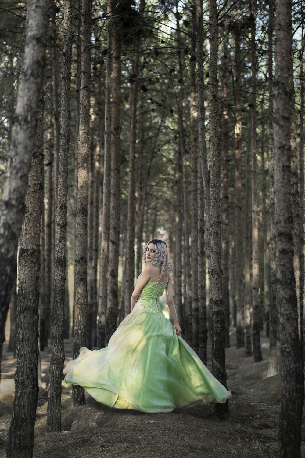 woman in green dress standing in the woods