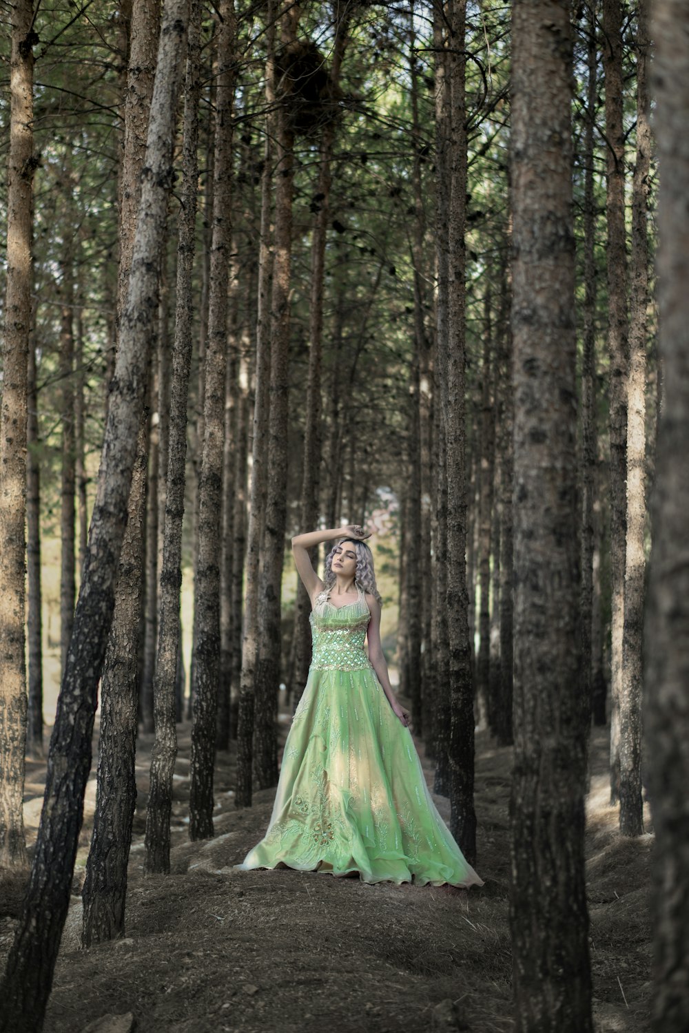 woman in green dress standing in the woods