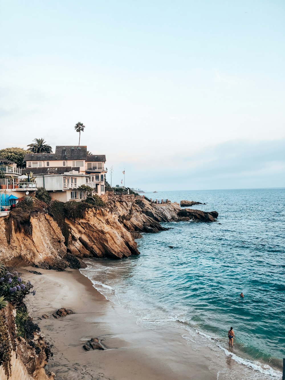 a sandy beach with houses on the cliff