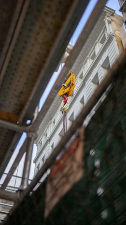 A close-up of a heavy-duty crane lifting a large steel beam at a construction site.