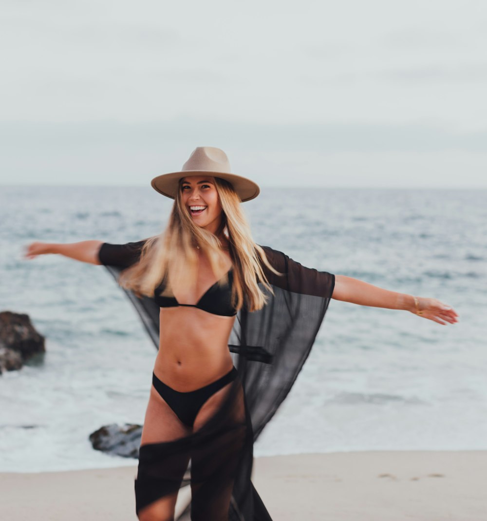 woman in black bikini standing on beach during daytime