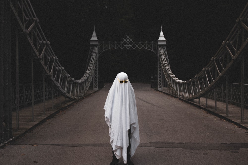 person in white robe walking on brown concrete bridge during nighttime