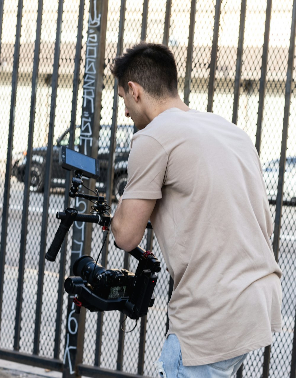 man in white t-shirt and black pants holding black camera