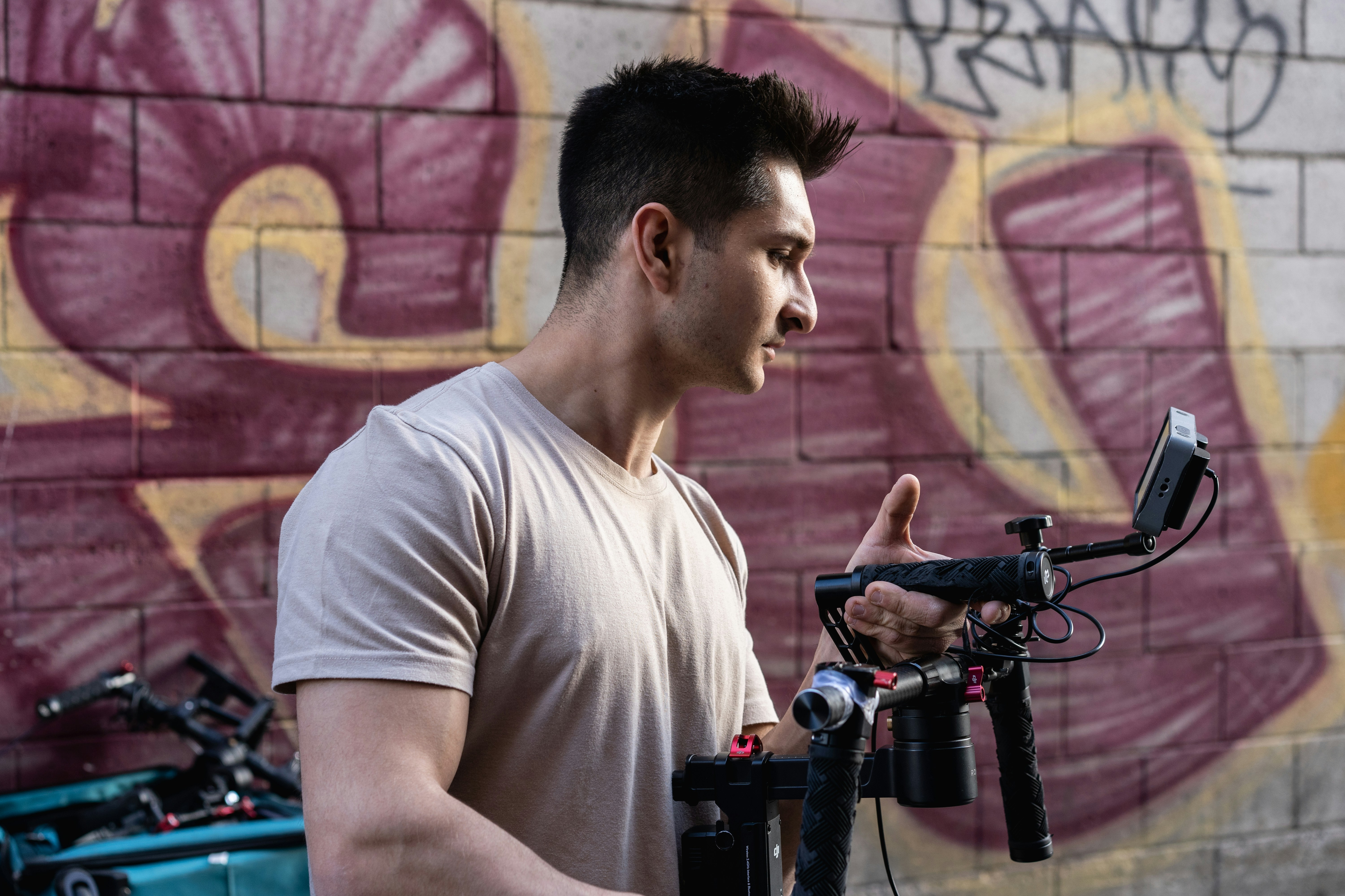 man in white crew neck t-shirt holding black video camera