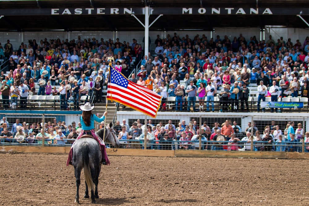 man riding white horse holding us a flag during daytime