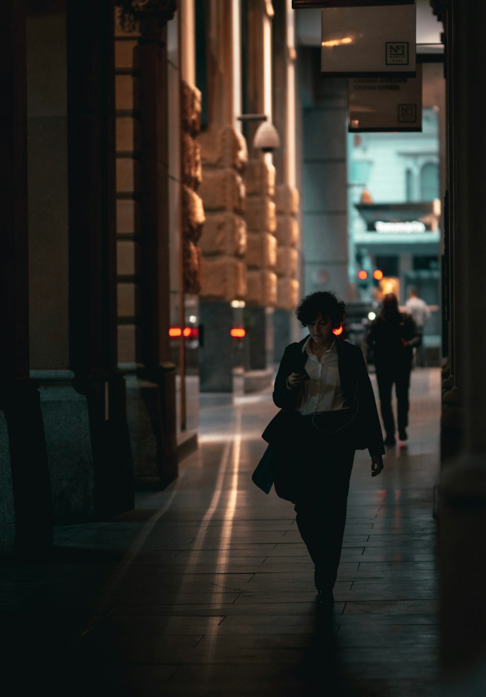 woman in black dress walking on sidewalk during night time