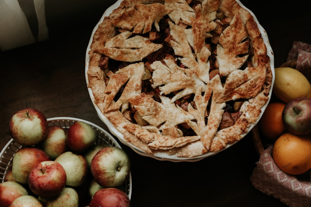 apple pie dish next to a bowl of apples and other fruit