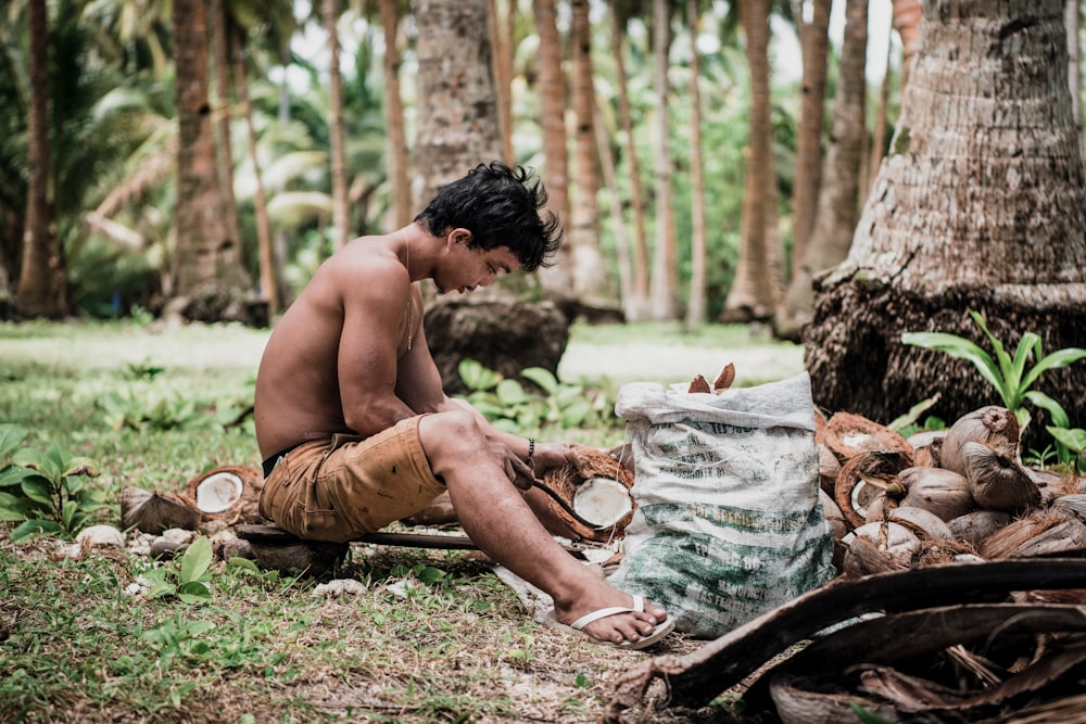 topless man sitting on tree log during daytime