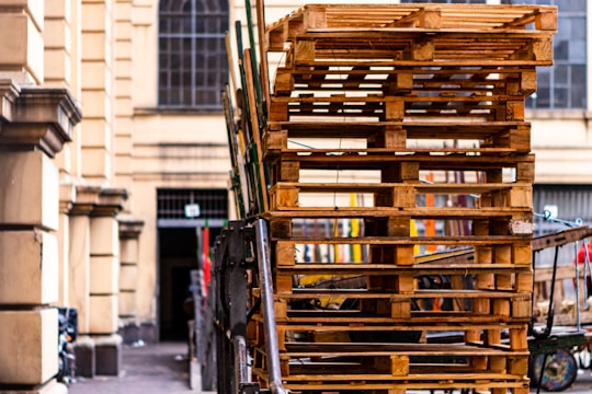 Stacks of wooden pallets ready for export at a shipping dock.