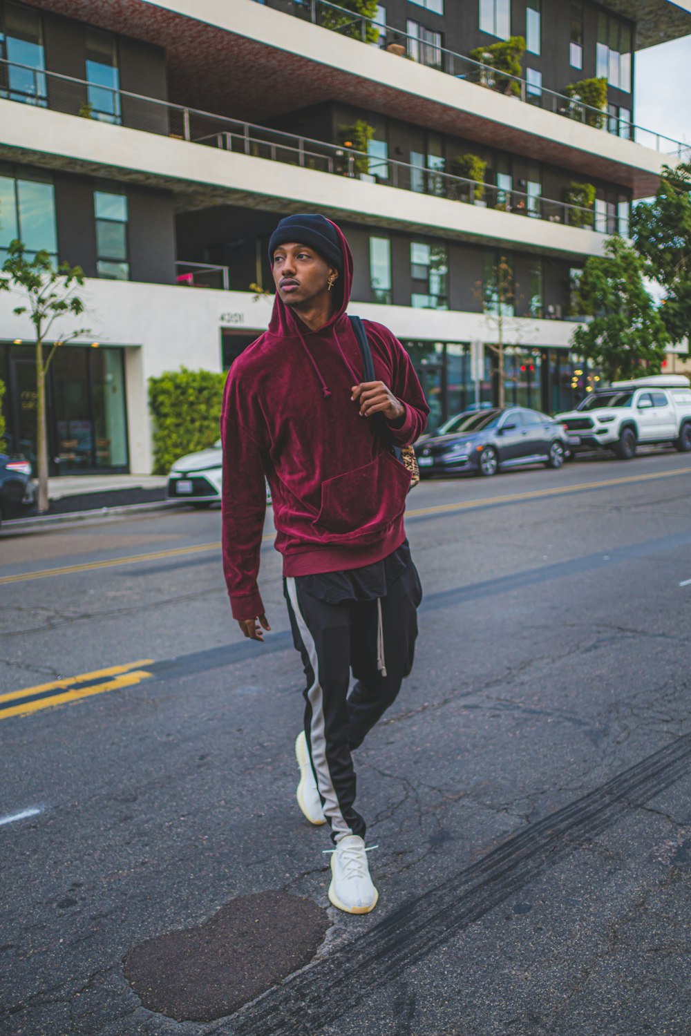 man in red hoodie standing on road during daytime