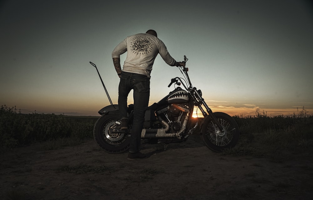 man in white shirt and blue denim jeans riding black and red motorcycle during sunset