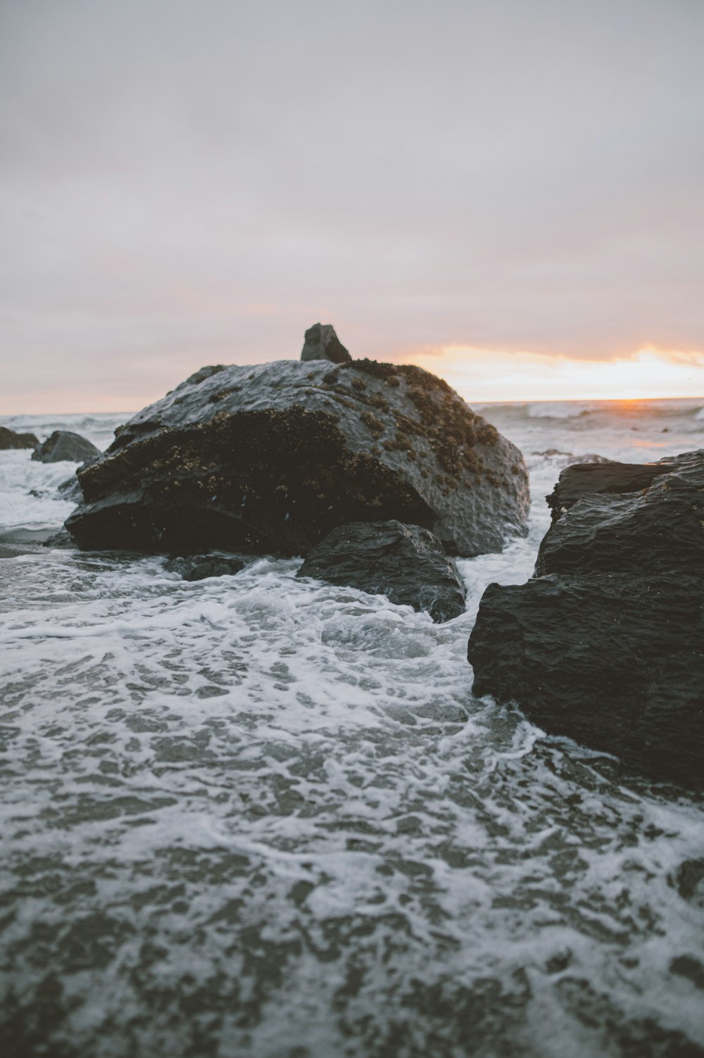 brown rock formation on sea during sunset